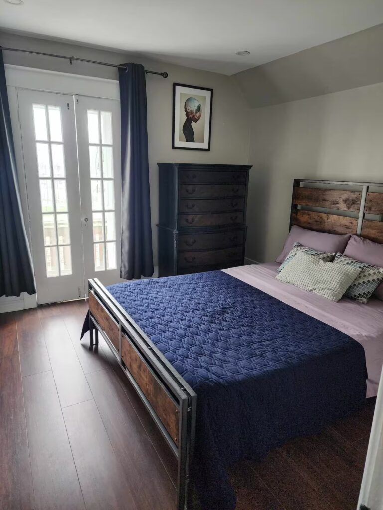 Furnished bedroom with purple bedding and windows in a Niagara Falls monthly rental