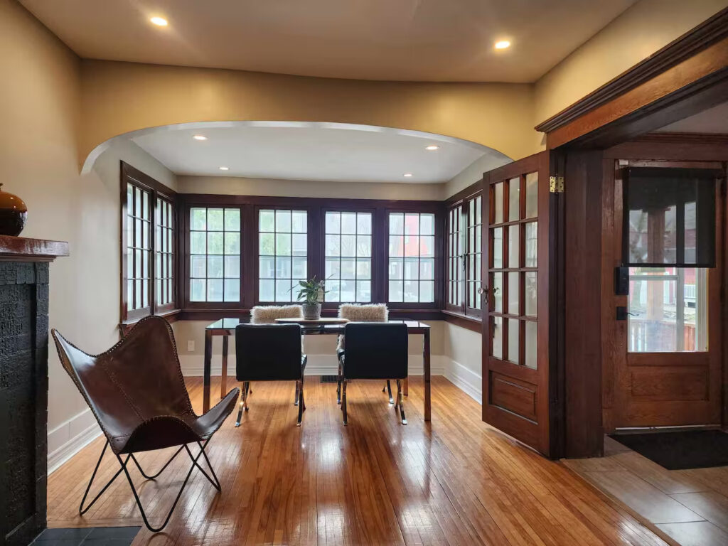 Dining area with a table and bay windows over hardwood floors in a furnished Niagara Falls home