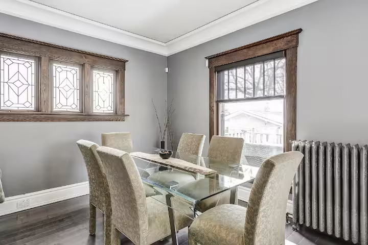 Dining room with a glass table and upholstered chairs in a furnished Niagara Falls home