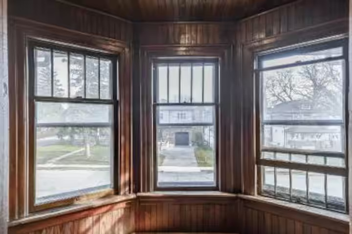 Sunroom with bay windows and hardwood floors in a furnished Niagara Falls home